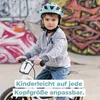 A young boy wearing a helmet is riding a balance bike in front of a graffiti-covered wall. Anteprima dell’immagine prodotto