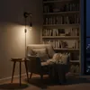 A cozy reading nook with a chair, side table, and bookshelf at night. Produktbild-Vorschau