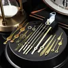 A collection of clock hands and a clock movement mechanism laid out on a black surface, with a portion of an hourglass visible in the background. Produktbild-Vorschau