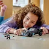 A young girl is playing with a LEGO Batmobile on the floor. Náhled obrázku produktu