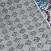 Close-up view of the underside of a rug with a diamond pattern, and a colorful rug partially visible on the right. Podgląd zdjęcia produktu