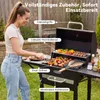 A woman is grilling food on a charcoal grill in a backyard setting. Anteprima dell’immagine prodotto