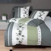 A neatly made bed with a duvet cover and pillows featuring a botanical print. Produktbild-Vorschau