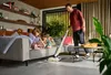 A man is vacuuming the floor in a living room while two children are reading on the couch. Anteprima dell’immagine prodotto