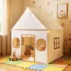 A child's play tent set up indoors on a colorful puzzle mat, decorated with string lights. Náhled obrázku produktu