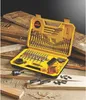 A yellow Dewalt drill bit set case is open, displaying a variety of drill bits and accessories. The case is placed on a surface with wooden planks and sawdust, suggesting a workshop or construction environment. Náhled obrázku produktu