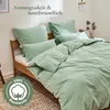 A neatly made bed with green bedding, pillows, and a duvet, set in a bedroom. Produktbild-Vorschau