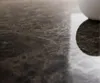 A close-up of a dark brown marble-like surface with a reflection of a white object. Produktbild-Vorschau