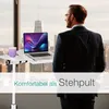 A man in a suit stands by a window looking out at a city skyline, with a laptop and mug on a mobile table in front of him. Anteprima dell’immagine prodotto