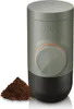 A portable espresso maker with a pile of coffee grounds next to it. Produktbild-Vorschau