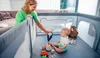 A mother plays with her baby inside a playpen, surrounded by toys. Anteprima dell’immagine prodotto