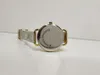 The back of a gold-colored watch with a mesh strap is shown on a white surface. Produktbild-Vorschau