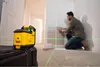A man is using a laser level to install wall panels in a room under renovation. Produktbild-Vorschau