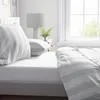 A close-up view of a bed with striped bedding and pillows. Produktbild-Vorschau
