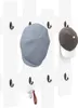 A white wall-mounted coat rack with several hooks, holding two caps and a set of keys. Náhľad obrázku produktu