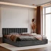A modern bedroom with a dark gray upholstered bed, complete with bedding and decorative elements. Podgląd zdjęcia produktu