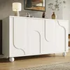 A white sideboard with decorative doors and spherical legs is shown in a room. Produktbild-Vorschau