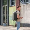 A young man with blonde hair walks outdoors, wearing a backpack and holding a smartphone. Anteprima dell’immagine prodotto