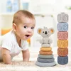 A baby is crawling on a carpet next to a stack of colorful baby toys. Voir les images du produit