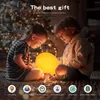 Two children are sitting on the floor looking at a glowing yellow lamp. Náhľad obrázku produktu