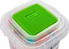 Close-up of the lid of a clear plastic container filled with colorful building blocks. The lid has a green square insert with raised studs, resembling a building baseplate. Voir les images du produit