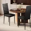 Two black dining chairs are placed around a round wooden dining table in a well-lit room. Náhľad obrázku produktu