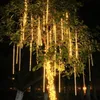 A tree decorated with warm white LED meteor shower lights at night. Náhled obrázku produktu