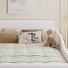 A close-up view of a bed with pillows and a stuffed monkey. Produktbild-Vorschau