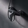 A close-up shot of a black shower faucet mounted on a dark gray textured wall. Produktbild-Vorschau