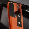 A close-up view of a black hook attached to an orange metal bracket, secured by screws. Produktbild-Vorschau