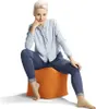 A woman is sitting on an orange cube ottoman. Náhled obrázku produktu