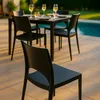 A set of black chairs and a table are arranged on a patio next to a swimming pool. Voir les images du produit