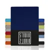 A stack of fabric swatches or samples in various colors, with a large navy blue swatch prominently displayed in the center. A black band with a white logo is visible at the bottom of the navy blue swatch. Produktbild-Vorschau
