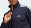 Close-up of a person wearing a navy blue Adidas tracksuit jacket. Produktbild-Vorschau