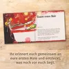 An open booklet with illustrations and text on a wooden surface. Produktbild-Vorschau