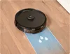 A black robot vacuum cleaner is shown on a wooden floor, cleaning a blue strip with white water drop icons. Produktbild-Vorschau