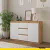 A modern sideboard with white doors and drawers, set against a neutral wall with artwork and a plant. Voir les images du produit
