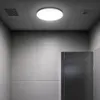 A ceiling light fixture in a room with tiled walls and a metal door. Náhľad obrázku produktu