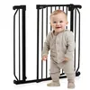 A baby stands in front of a black metal baby gate. Anteprima dell’immagine prodotto