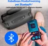 A person is holding a smartphone and interacting with a Bluetooth speaker in an outdoor setting. Produktbild-Vorschau
