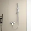 A chrome shower faucet and showerhead mounted on a light beige wall. Produktbild-Vorschau