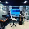 A music studio setup with acoustic wall panels, a desk with a computer monitor, audio equipment, and guitars. Produktbild-Vorschau