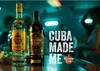 Two bottles of Havana Club rum are displayed on a bar counter in a dimly lit club with people in the background. Produktbild-Vorschau