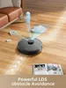 A robot vacuum cleaner is shown on a wooden floor, with arrows indicating its path and obstacles it avoids. A book and a piece of furniture are also visible. Náhled obrázku produktu