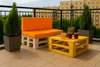A balcony with outdoor furniture, including a pallet sofa and coffee table, with drinks and a laptop. Anteprima dell’immagine prodotto