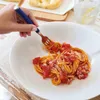 A hand is using a fork to eat spaghetti with tomato sauce from a white bowl. Produktbild-Vorschau