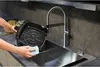 A person is cleaning the basket of an air fryer under a kitchen faucet. Produktbild-Vorschau