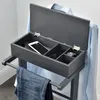 A valet stand with a shirt hanging on it and jeans draped over the bar, with an open storage compartment containing a phone, wallet, and watch. Produktbild-Vorschau