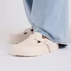 A close-up shot of a person wearing light blue jeans and pink Birkenstock Boston Eva clogs. Podgląd zdjęcia produktu