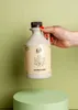 A hand holding a bottle of maple syrup. Produktbild-Vorschau